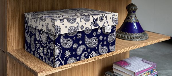 Paisley Storage Box. The box is adorned with a Paisley motif. The lid of the box has a white background whilst the box itself has a dark blue background.