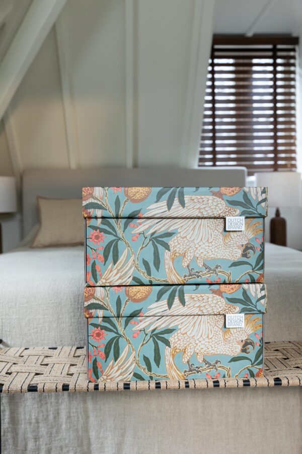 The Cockatoo and Pomegranate Storage Box with a vibrant print of cockatoos and pomegranates. The box features detailed illustrations of white cockatoos with yellow crests among green leaves and red pomegranates on a soft blue background. The artwork has a botanical and tropical aesthetic.