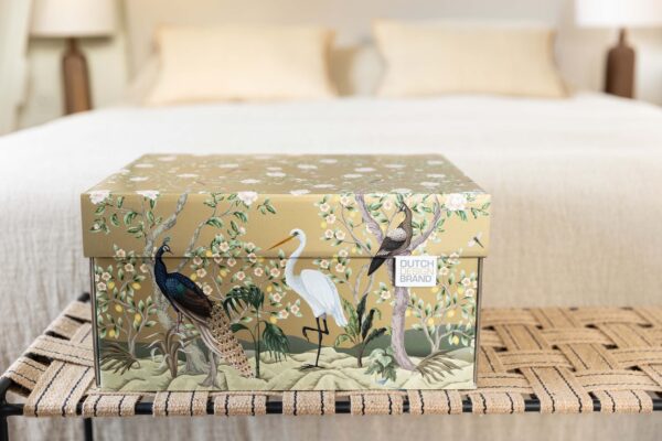 A storage box adorned with the "Golden Paradise" design, showcasing a variety of birds such as a peacock and a white heron amidst lush flora and fauna on a gold background. The box is detailed with illustrations of blooming white flowers, lemon fruits, and dragonflies.