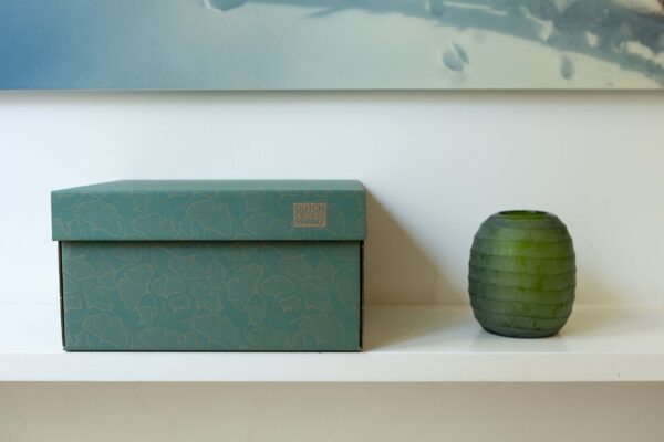 A teal storage box with a gorgeous ginkgo leaf pattern and "DUTCH DESIGN BRAND" printed in brown on the lid.